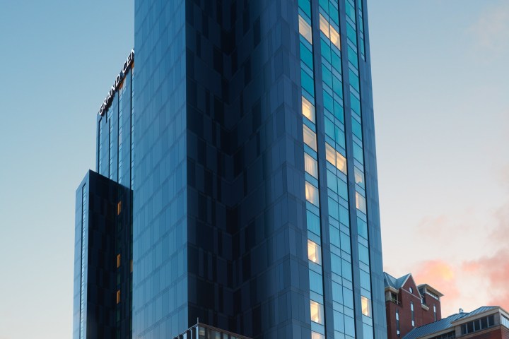 Tall modern building with glass facade at sunset, labeled Grand Central.
