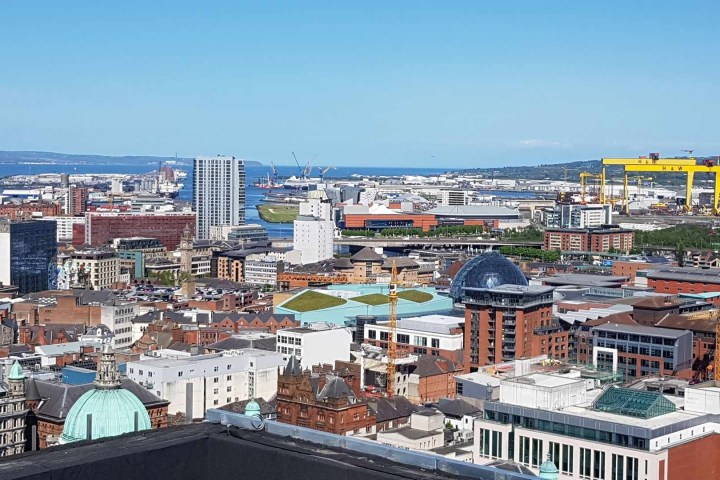 Aerial view of a city skyline with buildings, cranes, and a harbor.