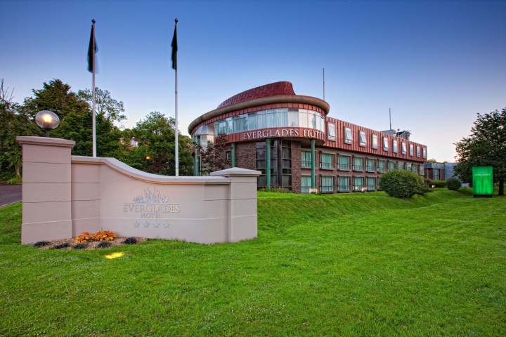 Exterior view of Everglades Hotel with green lawn and blue sky.