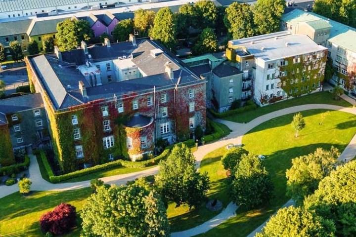 Aerial view of ivy-covered building, trees, and pathways on a sunny day.