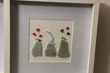 Framed artwork of three abstract vases with red flowers on a windowsill.