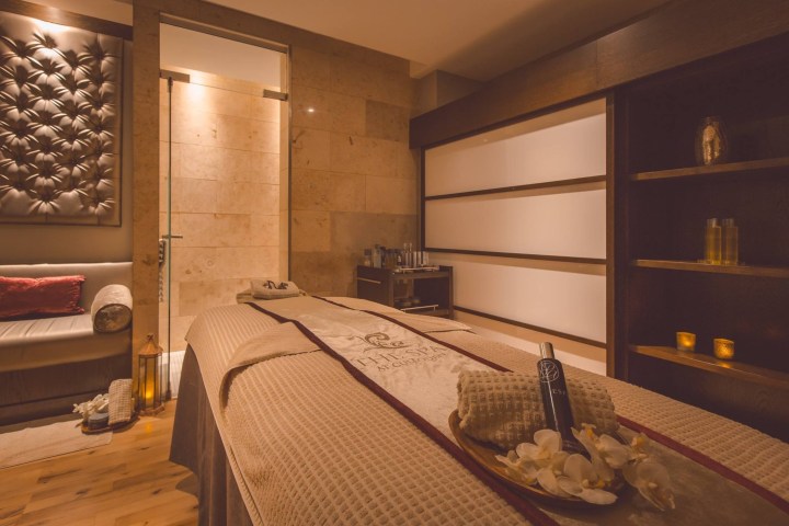 Tranquil spa room with a massage bed, soft lighting, and soothing decor.