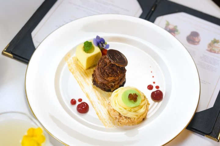 Elegant dessert trio with chocolate, cream mousse, and drink on a white table with menus.