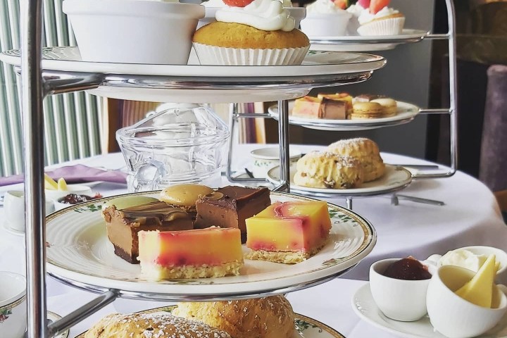 Afternoon tea stand with scones, pastries, and cupcakes on a table.