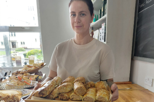 Person holding a tray of pastries with a window in the background.