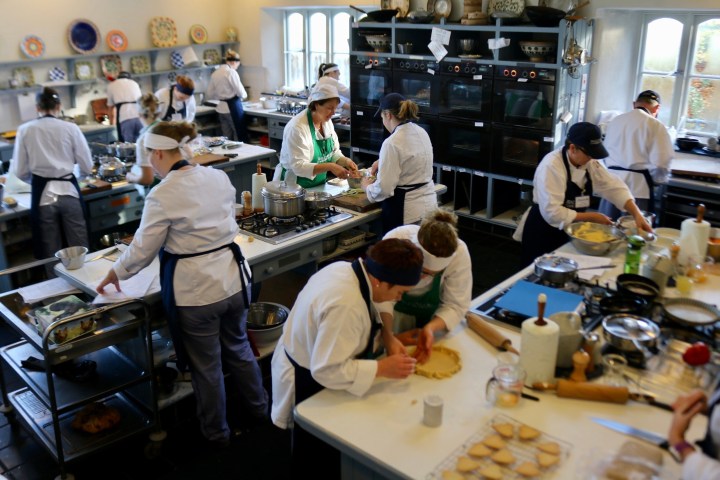 People in chef uniforms cooking in a busy professional kitchen.