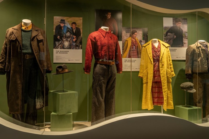 Exhibit of vintage clothing with movie posters in a display case.