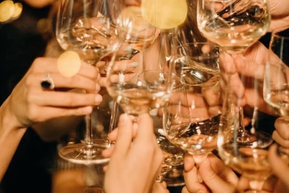 Group of people clinking wine glasses in a celebratory toast.
