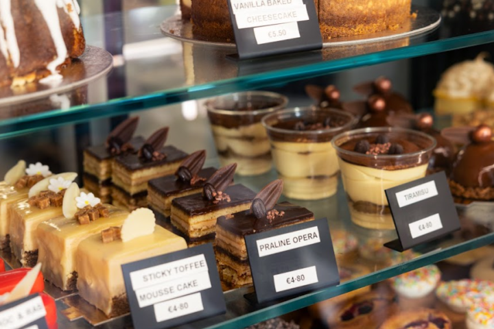 Assorted pastries on display in a bakery case with labels and prices.