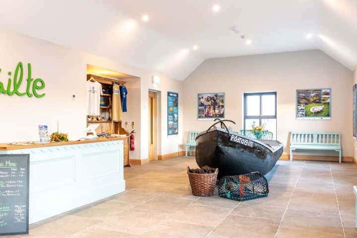 Lobby with Failte sign, boat display, tasting menu board, and informational posters on walls.