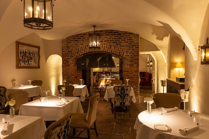 Cozy restaurant with arched ceilings, brick wall, and candlelit tables set for dining.