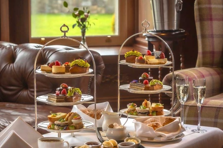 Elegant afternoon tea setup with tiered trays of pastries, tea cups, and champagne glasses.