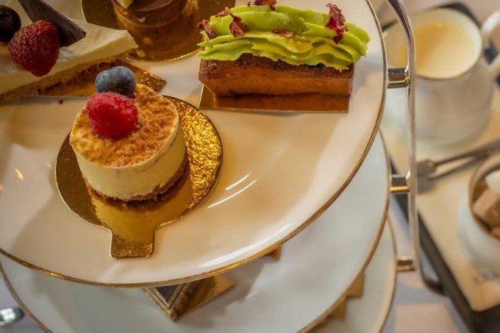 Tiered dessert tray with assorted pastries and a pot of cream.