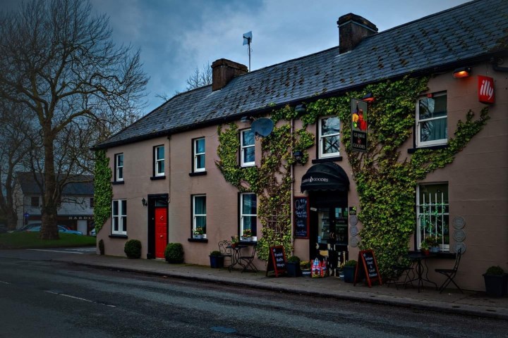 Ivy-covered building with a cafe entrance on a quiet street.