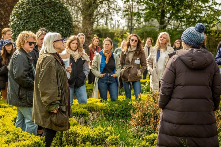 Group of people listening to a speaker in a garden setting.