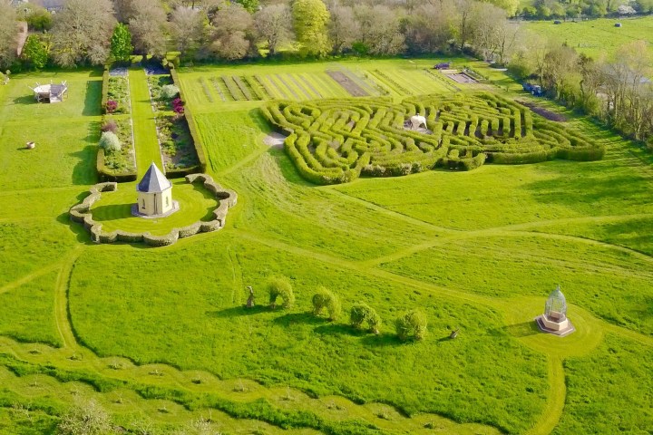 Aerial view of a large garden with hedges, paths, and a small tower.