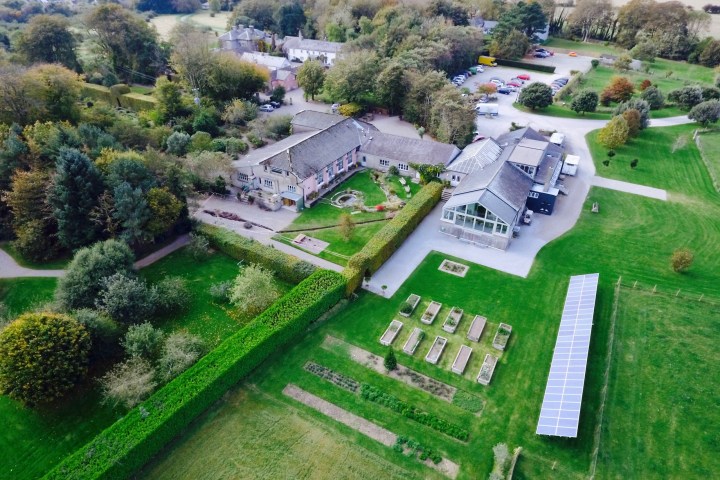 Aerial view of a landscaped estate with buildings, gardens, and solar panels.