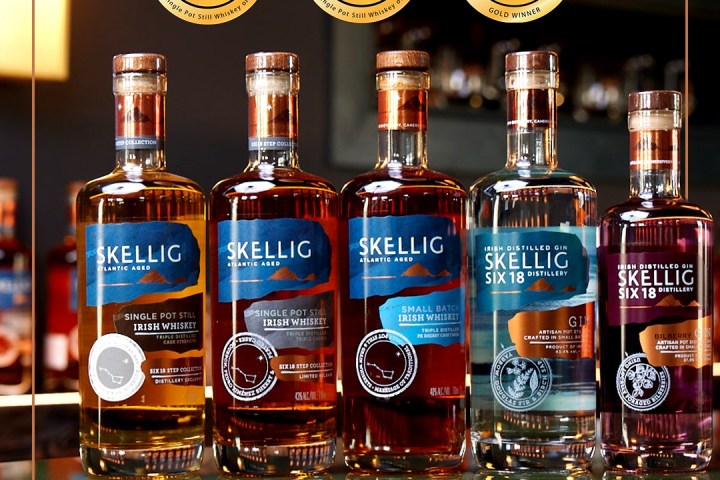 Five Skellig spirit bottles on a reflective surface with award medallions above.