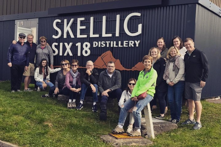 Group of people posing in front of Skellig Six 18 Distillery sign.