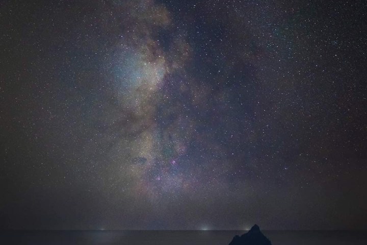 Starry night sky with distant islands silhouetted against the Milky Way galaxy.
