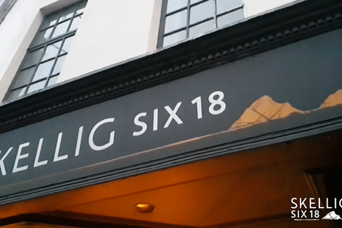 View of Skellig Six18 sign on a building with large windows above.