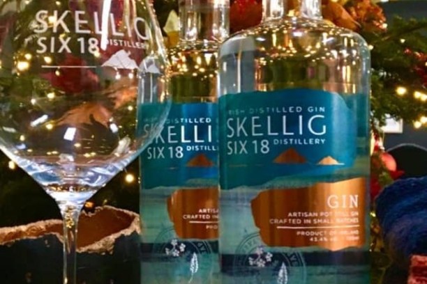 Two Skellig Six 18 gin bottles and a glass with Christmas decor.