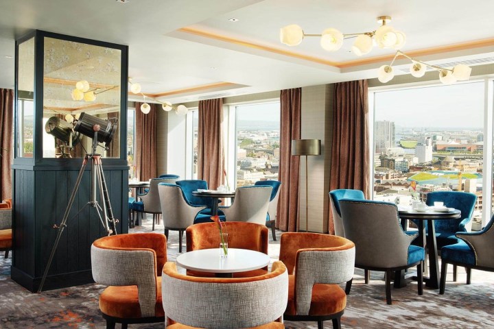 Bright lounge with modern decor, round tables, and city view through large windows.