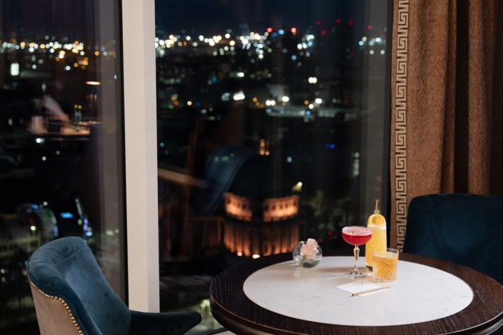 Elegant table with drinks against city nightscape view from window.