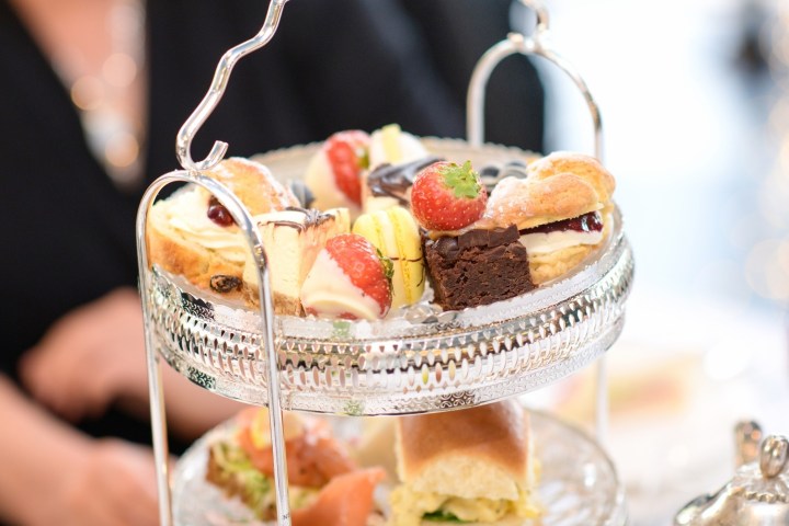 Two-tiered tray with assorted desserts and pastries, including brownies and fruit-topped items.