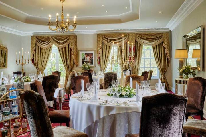 Elegant dining room with chandeliers, round tables, and ornate curtains.