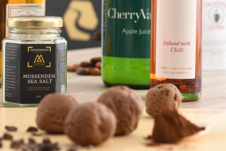 Various jars and bottles with cocoa truffles on a wooden surface.