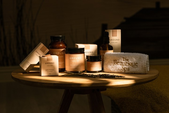 Assorted spa products labeled 'Ground' on a wooden table with a branded towel.