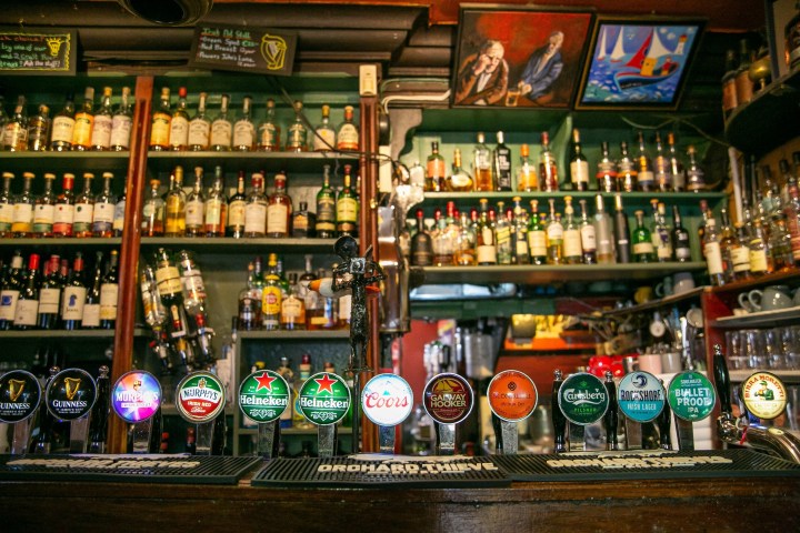 Bar interior with various liquor bottles and 12 beer taps, including Guinness and Heineken, on the counter.
