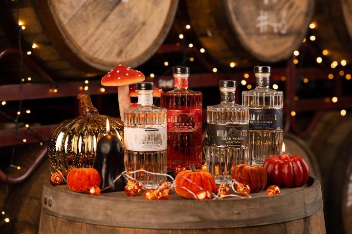 Bottles on a barrel with pumpkins, mushroom, and string lights.
