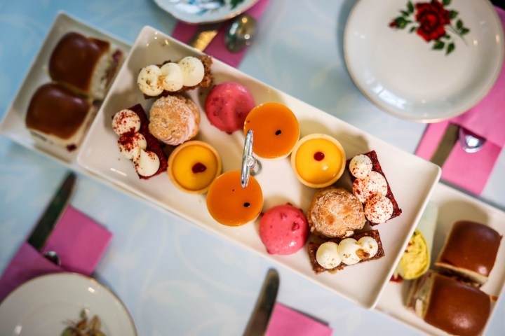 Dessert platter with assorted pastries and colorful sweets on a white tray.