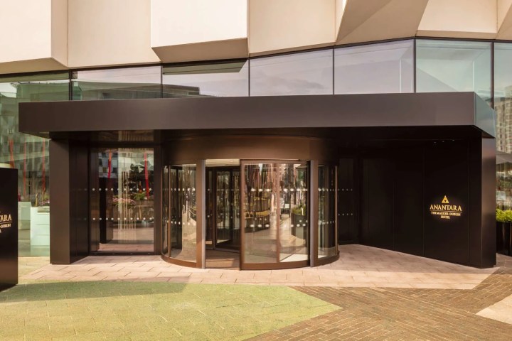 Modern building entrance with revolving door and Anantara hotel sign.