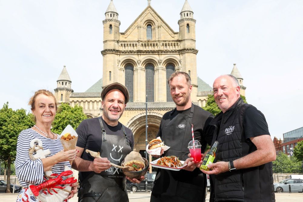 Four people holding food and drinks in front of a cathedral.
