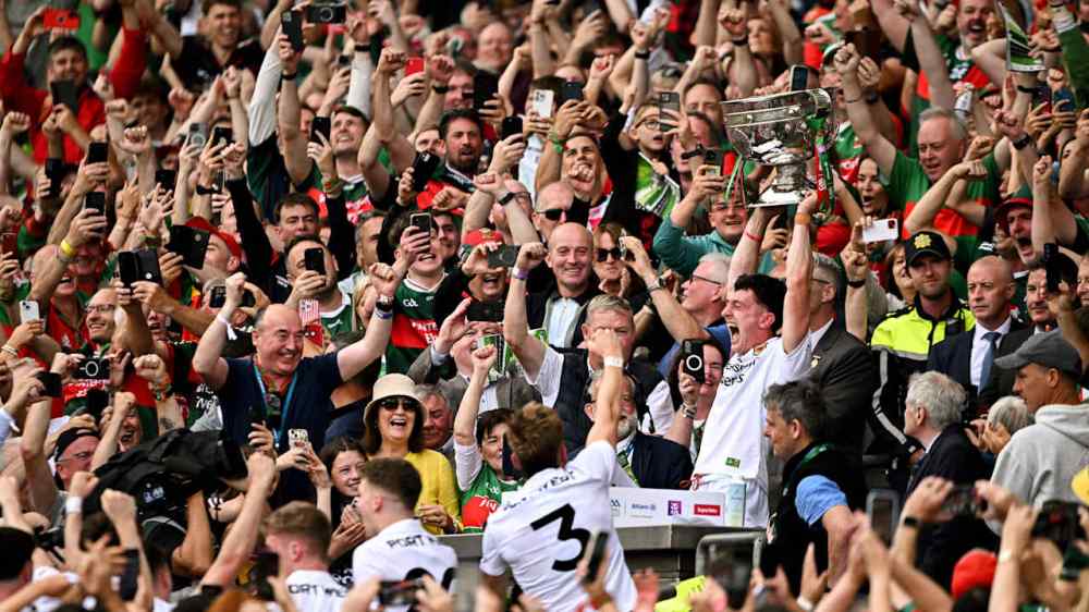 Crowd celebrating with a sports trophy held up by a player.