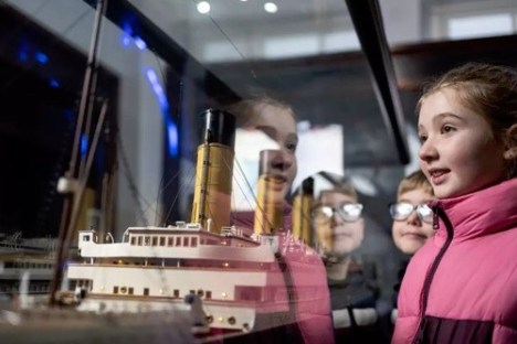 Kids looking at a ship model in a display case.