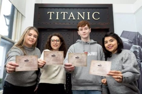 Four people holding tickets in front of a Titanic exhibit.