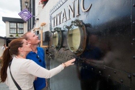 Two people looking at Titanic museum exhibit with portholes.