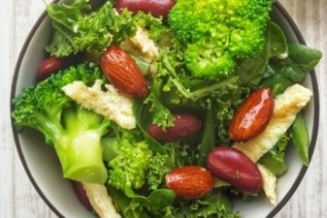 Salad with broccoli, almonds, red beans, and greens in a bowl.