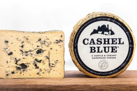 Cashel Blue cheese wedge and wheel on a wooden surface.