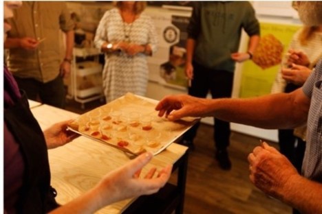 People sampling small portions on a tray in a kitchen setting.