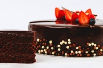 Chocolate cake with berries and a slice cut out on white background.