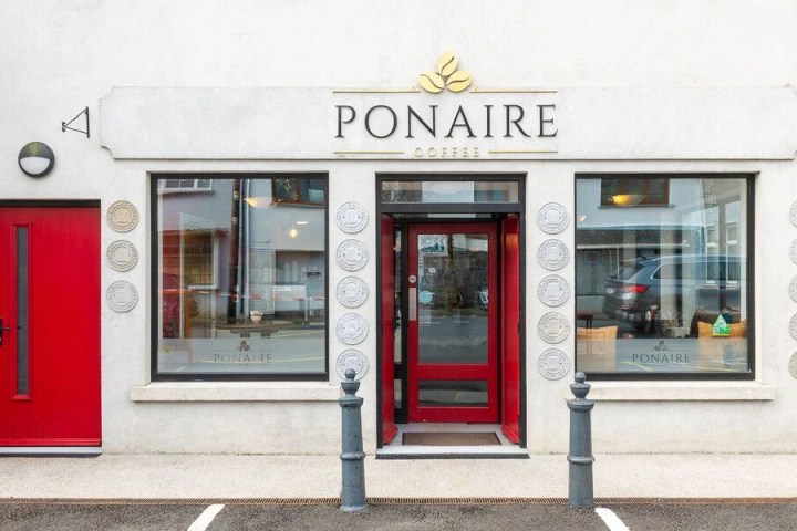 Coffee shop exterior with red doors and large windows.