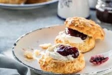 Scone with cream and jam on a plate, napkin on side.