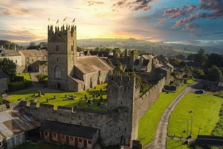 Aerial view of a historic castle and church at sunset in a rural landscape.
